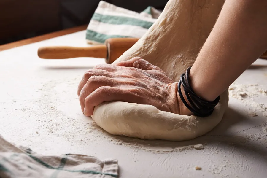 Pétrissage à la main d'une pâte à pain sur un plan de travail fariné